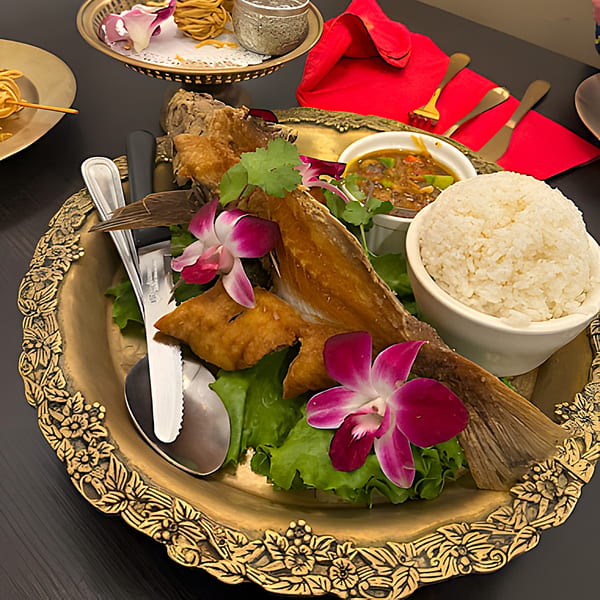 Crispy fried fish with rice, sauce, and orchids on a decorative golden platter at Siam Nara Thai Cuisine.