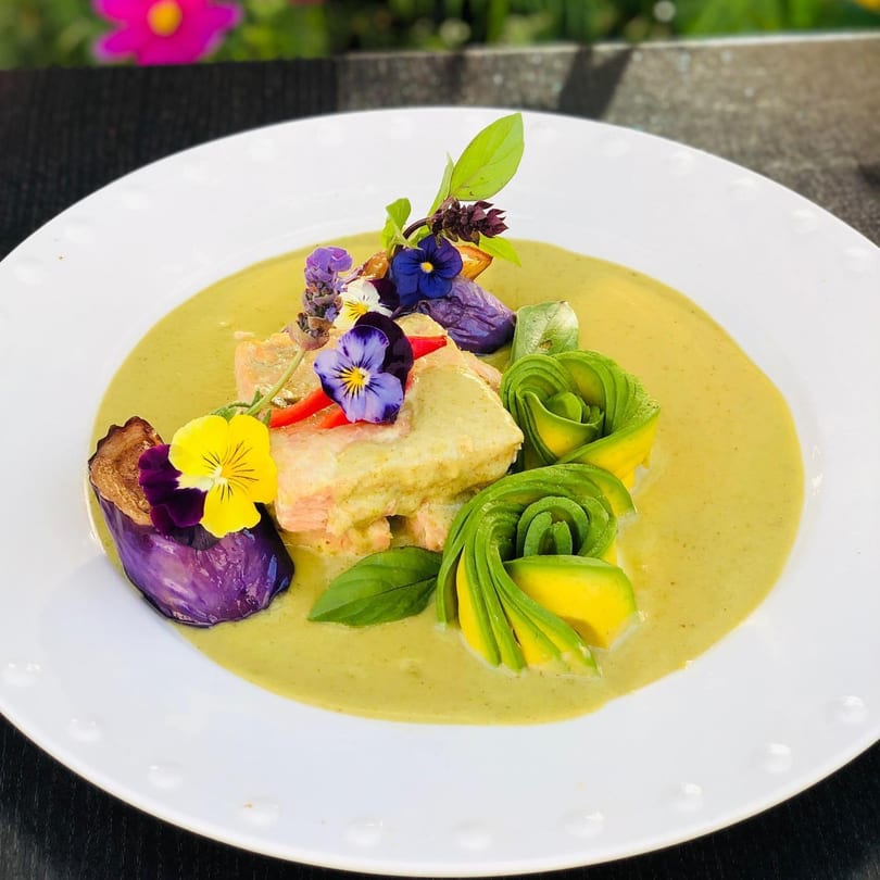 Siam Nara Thai Cuisine's green curry with salmon, avocado roses, purple eggplant, and edible flowers.