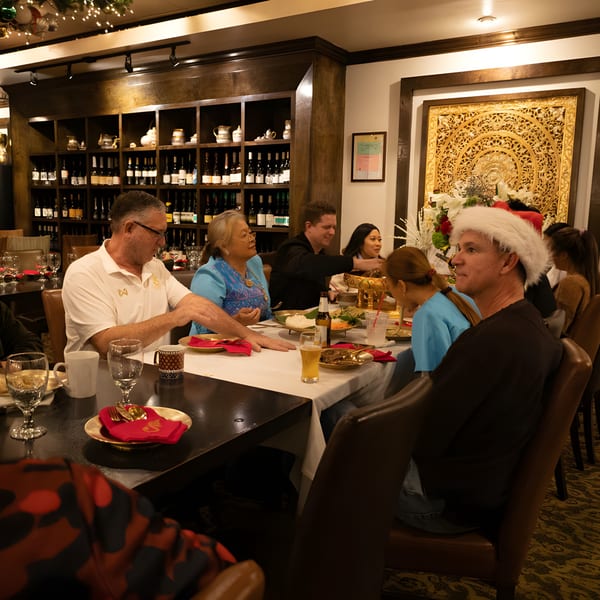 Diners enjoying a meal at Siam Nara Thai Cuisine, with a man in a Santa hat at the table.