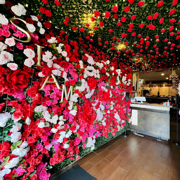 A vibrant floral wall with red, pink, and white flowers, spelling "SIAM" in gold letters.