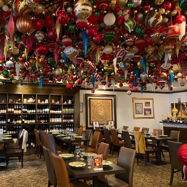 Siam Nara Thai Cuisine dining room with tables set, wine shelves, and a ceiling full of colorful ornaments.