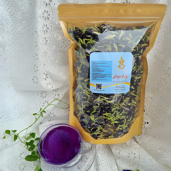A bag of dried butterfly pea flowers next to a glass of vibrant purple butterfly pea tea.
