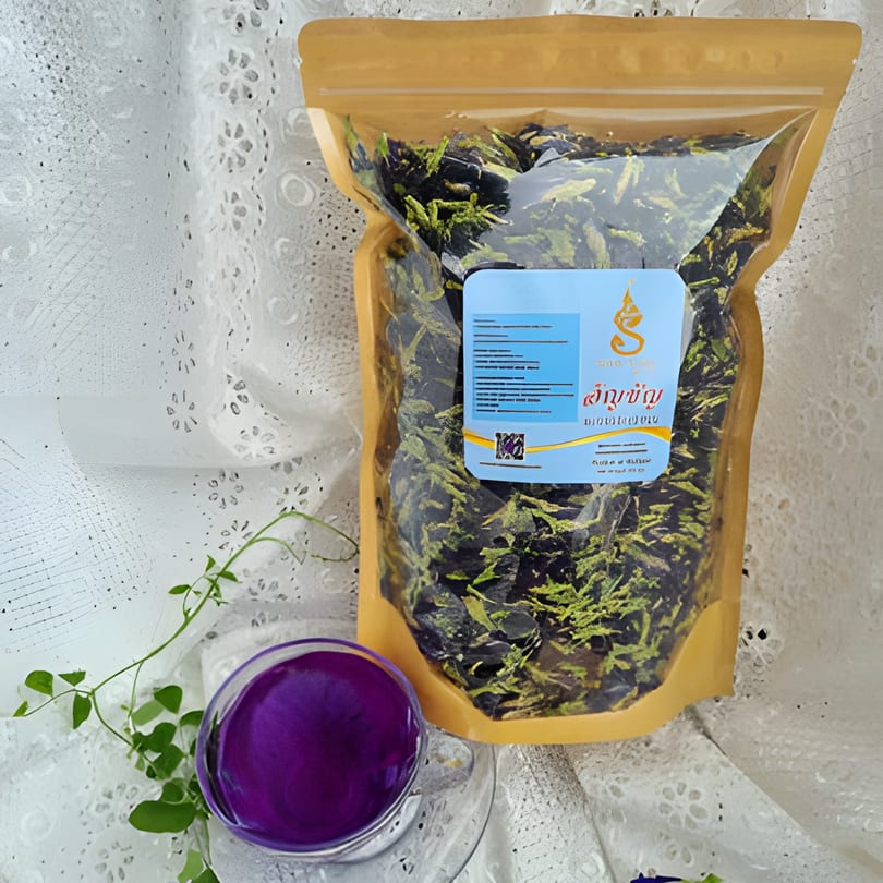 A bag of dried butterfly pea flowers next to a glass of vibrant purple butterfly pea tea.