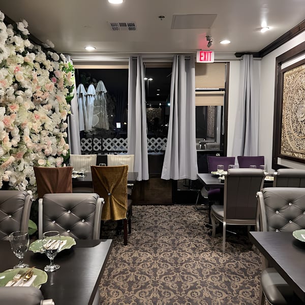 Elegant dining room at Siam Nara Thai Cuisine with floral wall, set tables, and patterned carpet.